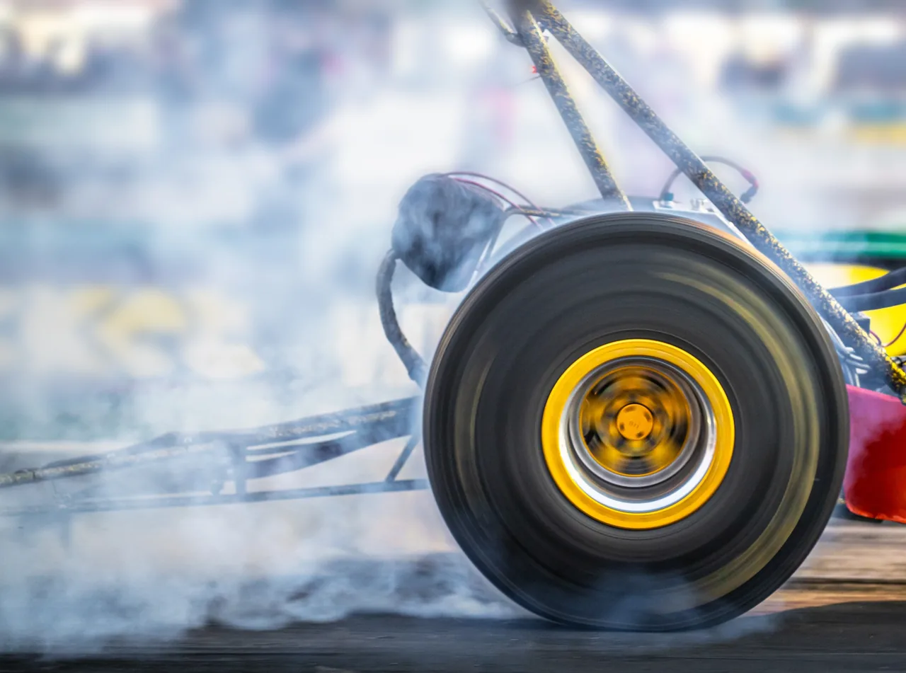 A dragster wheel spinning through coloured smoke